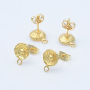 May include: Four gold-colored stud earrings with textured, round faces and post backs. Each earring has a small loop at the bottom. The earrings are displayed on a white surface.
