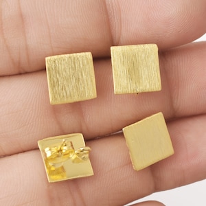 Op de afbeelding: Een paar gouden vierkante oorbellen met een geborstelde afwerking. De oorbellen hebben een oorbelsteker en een vlinder sluiting.
