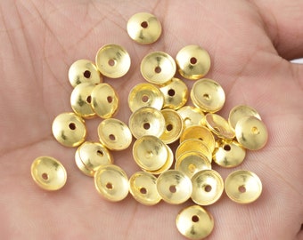 Può includere: Un mucchio di cappucci per perline in metallo dorato. I cappucci sono rotondi e hanno un piccolo foro al centro. Sono comunemente usati nella creazione di gioielli.