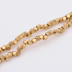 May include: A strand of gold-colored faceted beads. The beads are small and have a slightly irregular shape.