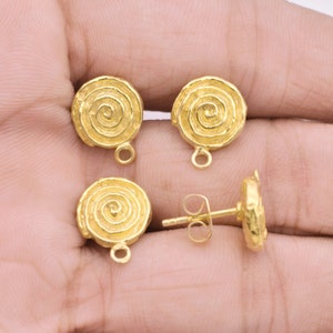 May include: A set of gold-tone earrings with a spiral design. The earrings are made of metal and have a textured finish.