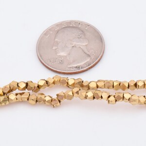 May include: A strand of gold-colored faceted beads, approximately the size of a US quarter.