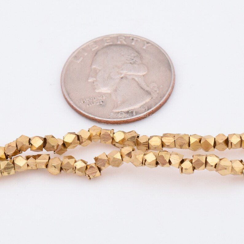 May include: A strand of gold-colored faceted beads, approximately the size of a US quarter.