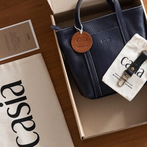 Casia navy leather bag inside gift packaging box with brand materials