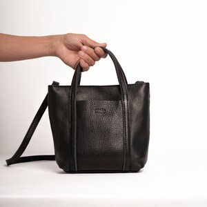 Black leather crossbody bag with top handle on white background