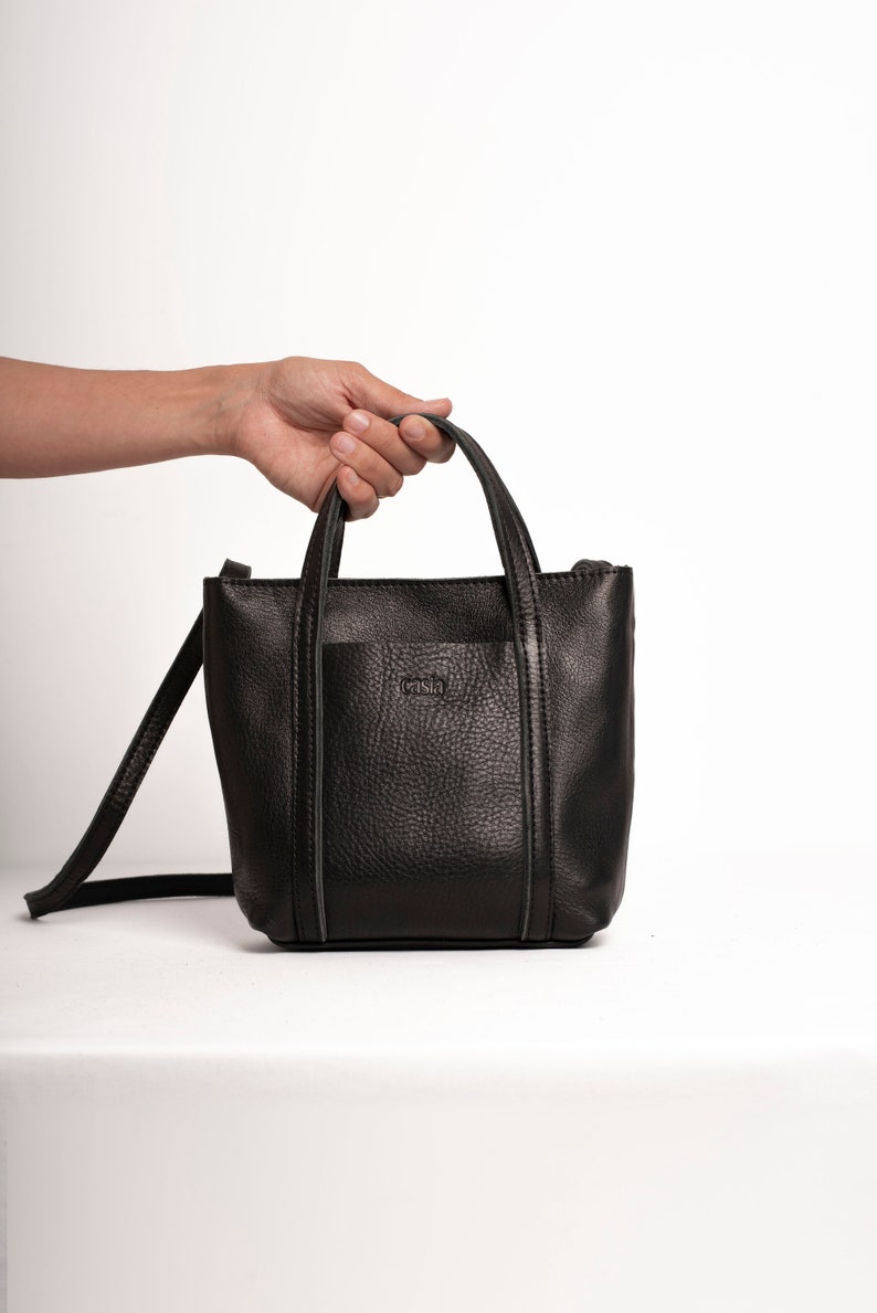 Black leather crossbody bag with top handle on white background
