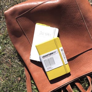 Caramel leather backpack open showing contents and notebook, handmade full grain leather diaper bag