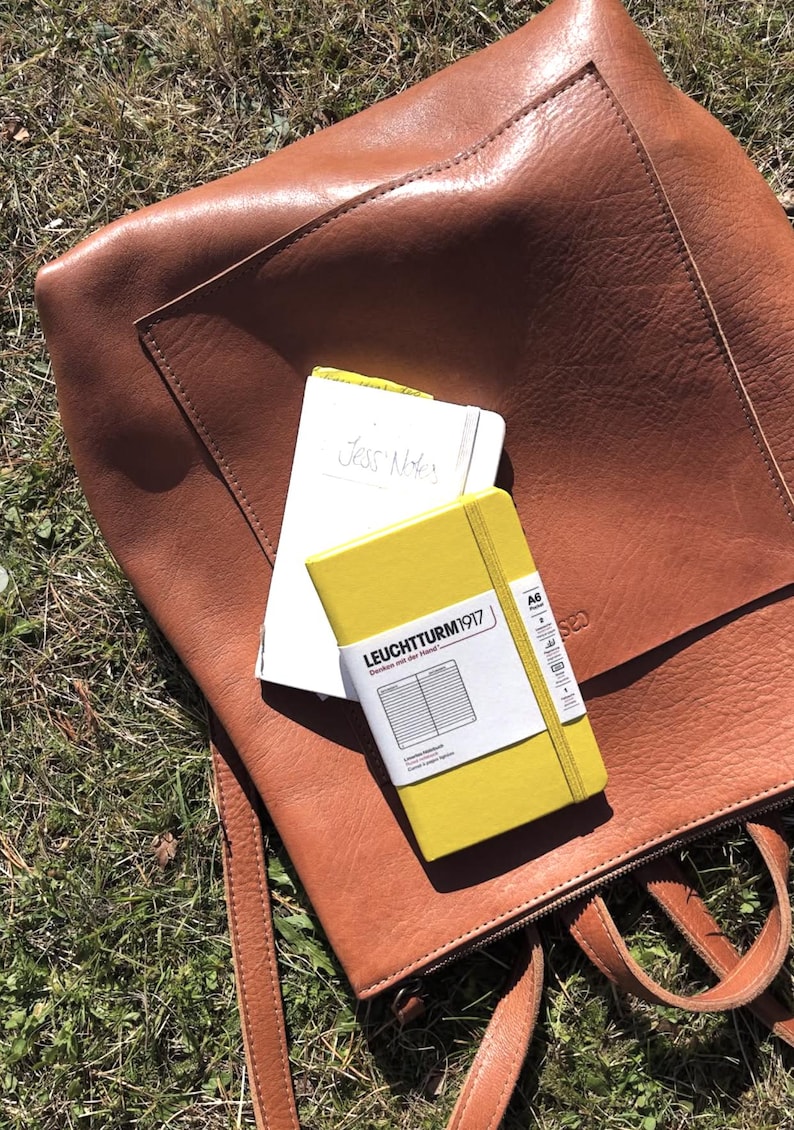 Caramel leather backpack open showing contents and notebook, handmade full grain leather diaper bag