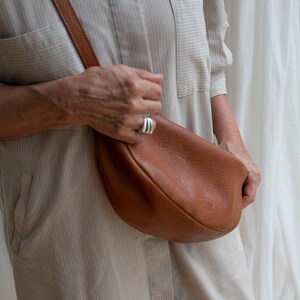 Woman wearing tan leather moon shape bag in, handmade full grain leather crossbody sling bag lifestyle