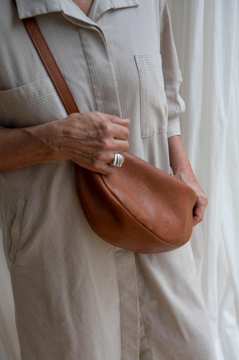 Woman wearing tan leather moon shape bag in, handmade full grain leather crossbody sling bag lifestyle