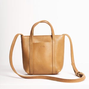 Mustard yellow leather tote bag with adjustable strap on white background