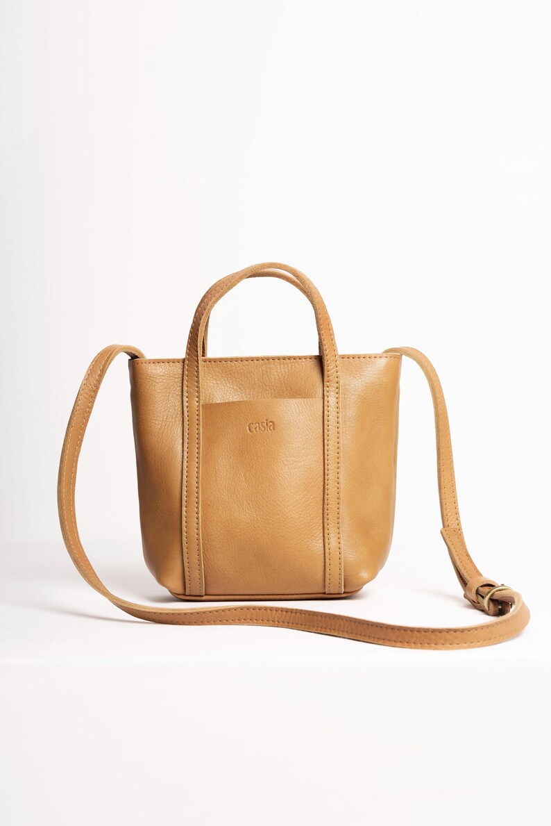 Mustard yellow leather tote bag with adjustable strap on white background