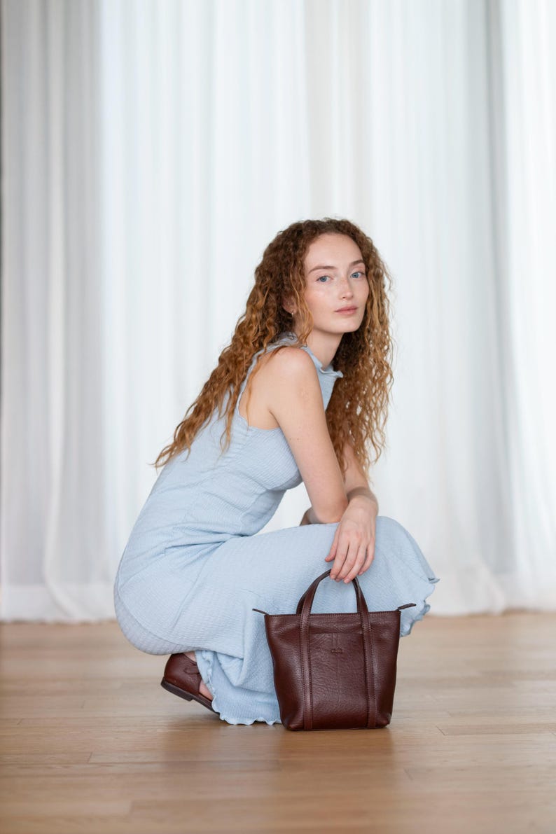 Woman sitting with bordeaux leather tote bag showing everyday city use