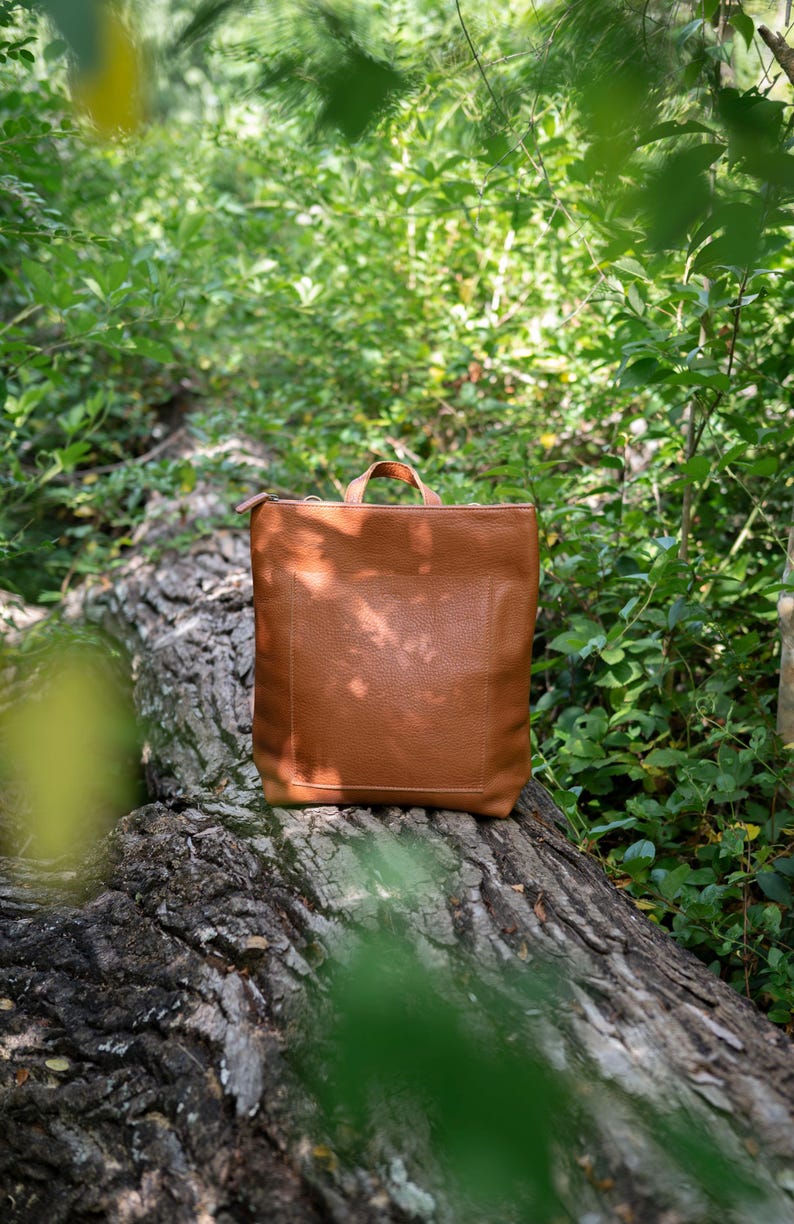 Caramel leather convertible backpack in garden setting, full grain vegetable tanned handmade leather bag