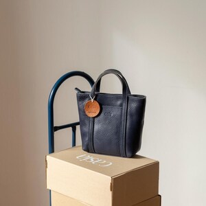 Navy leather bags stacked on wooden boxes showing depth and structure