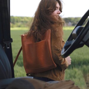 Woman outdoors with caramel leather convertible backpack, full grain vegetable tanned leather bag for women