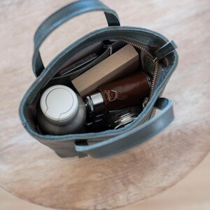 Open leather bag interior with phone wallet and daily essentials for scale