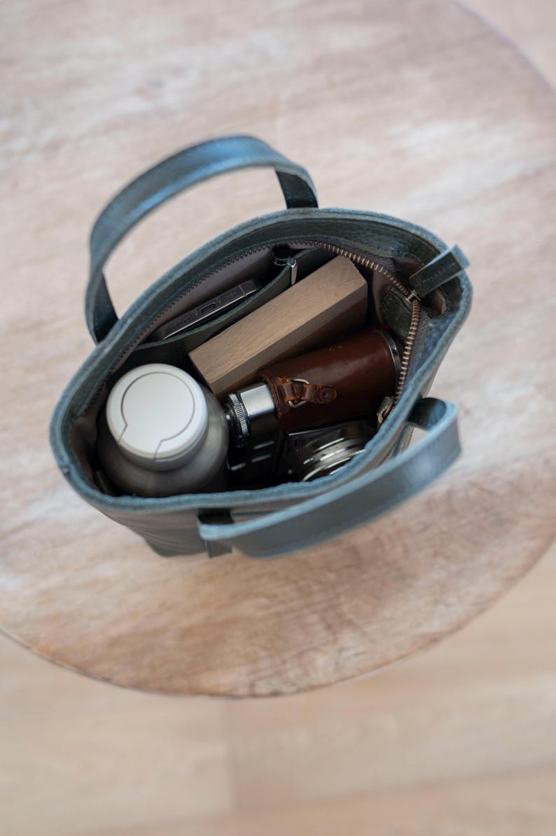 Open leather bag interior with phone wallet and daily essentials for scale