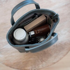 Open leather bag interior with phone wallet and daily essentials for scale