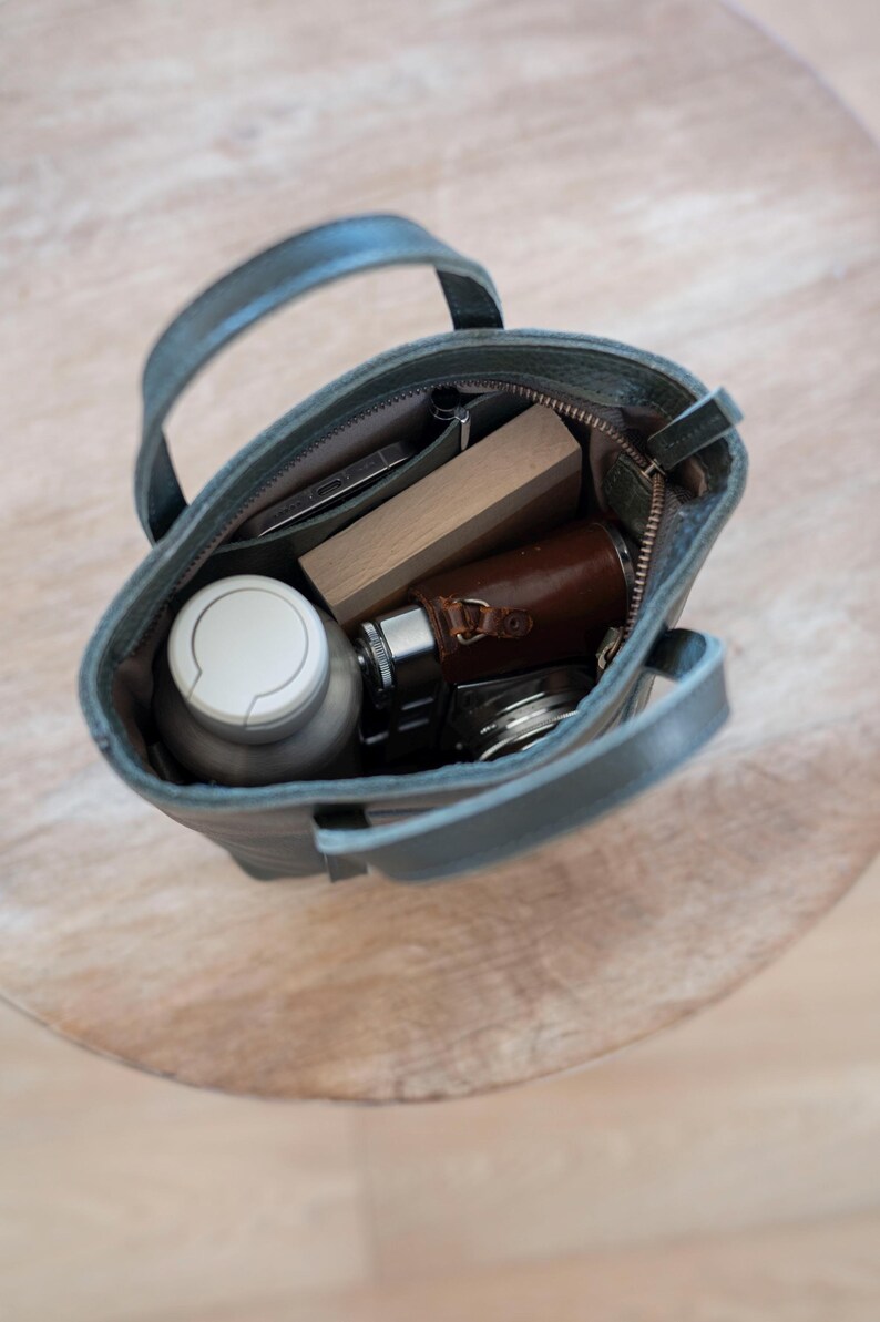 Open leather bag interior with phone wallet and daily essentials for scale