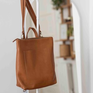 Caramel full grain leather convertible tote bag hanging on rack, handmade vegetable tanned leather shoulder bag