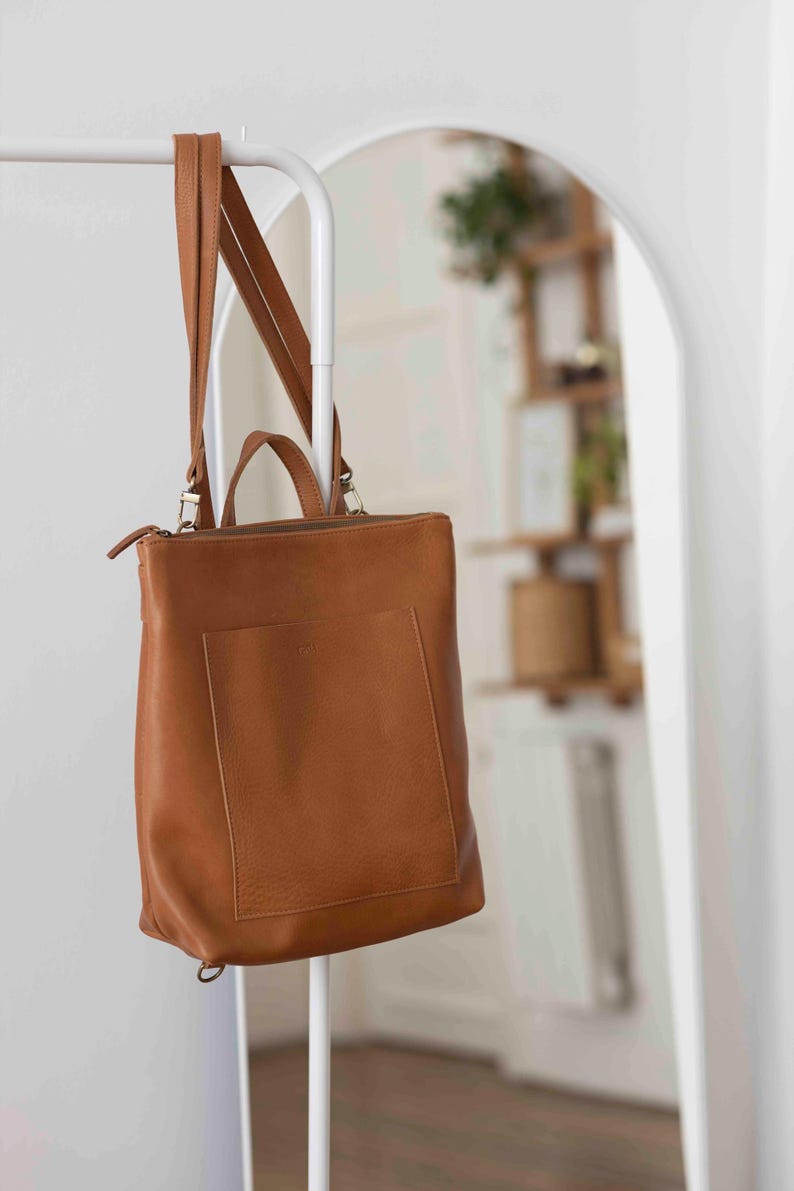 Caramel full grain leather convertible tote bag hanging on rack, handmade vegetable tanned leather shoulder bag