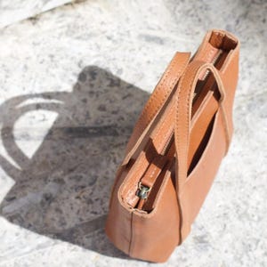 Aerial view of brown leather bag showing texture and adjustable strap hardware