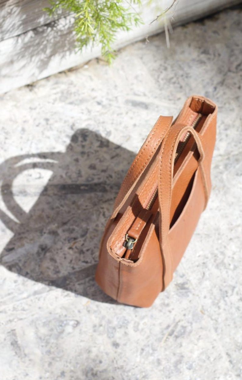 Aerial view of brown leather bag showing texture and adjustable strap hardware