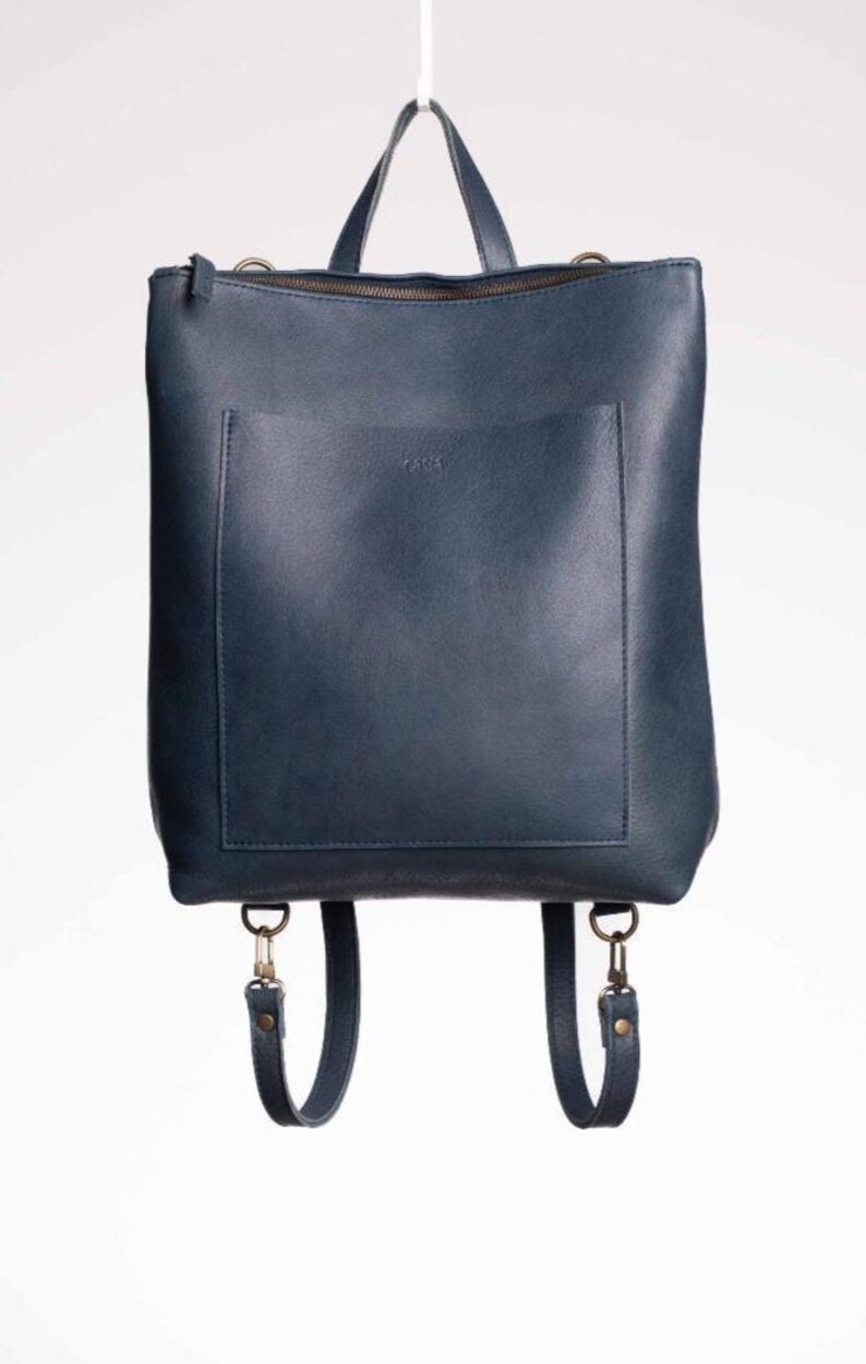 Navy blue full grain leather convertible backpack front view on white background, handmade leather rucksack