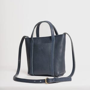 Navy Blue leather bag with adjustable crossbody strap on white background