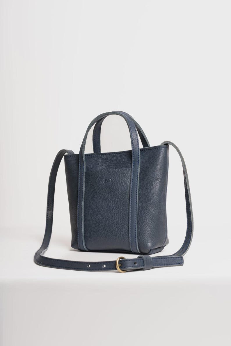 Navy Blue leather bag with adjustable crossbody strap on white background