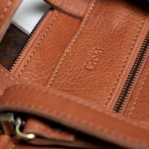 Close up of caramel leather backpack stitching and zipper detail, handmade full grain vegetable tanned leather
