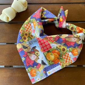 May include: A blue and white bandana with a patchwork design featuring scarecrows, pumpkins, sunflowers, and the text "mostly sunny".