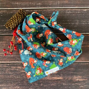May include: A blue bandana with a Christmas pattern of Santa Claus figures, snowflakes, and Christmas trees. The bandana has a snap closure and a small label that says "notty sunny".