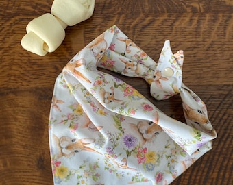 May include: White bandana with a floral pattern featuring bunnies and flowers. The bandana has a snap closure and a small label that says "Milly Sews".