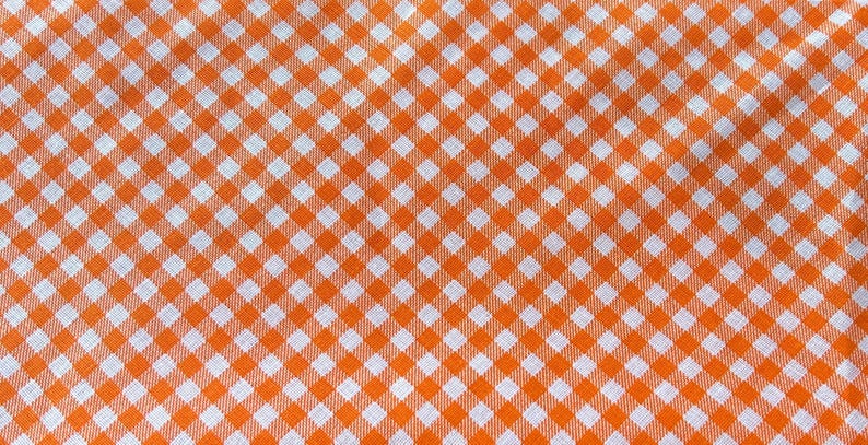 May include: Orange and white checkered fabric with a repeating pattern of squares.