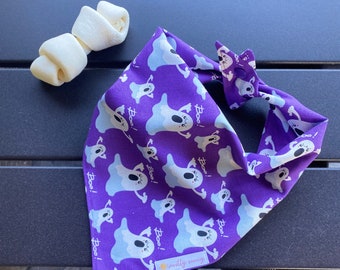 May include: Purple bandana with a ghost pattern and the text "Boo!" repeated throughout. The bandana has a white label with the text "mostly sunny".