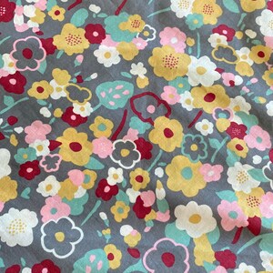 May include: A gray fabric with a floral pattern. The flowers are in shades of pink, yellow, white, and red. The fabric has a vintage feel.