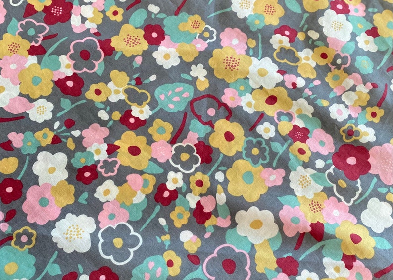May include: A gray fabric with a floral pattern. The flowers are in shades of pink, yellow, white, and red. The fabric has a vintage feel.