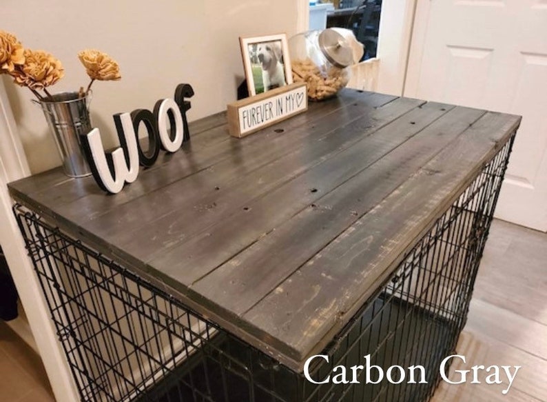 May include: A black metal dog crate with a wooden top painted in a carbon grey colour. The top has a sign that says "Forever in my heart" and the word "woof" is spelled out in white letters on the top.