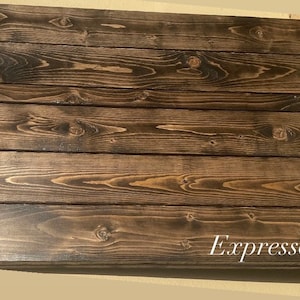 May include: Close-up of a dark brown wood surface with a natural wood grain pattern. The wood has a smooth, polished finish. The text "Espresso" is written in white on the bottom right corner of the image.