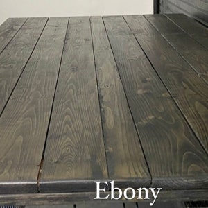 May include: Close-up of a dark wood table top with a smooth, polished finish. The wood grain is visible and the colour is a deep ebony.