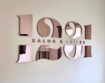 May include: A rose gold mirrored sign with the text "121 Salon & Suites" in white letters.
