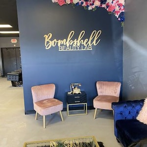 A professional beauty salon showcasing a custom 3D laser-cut logo sign on the wall, crafted in acrylic with raised lettering.