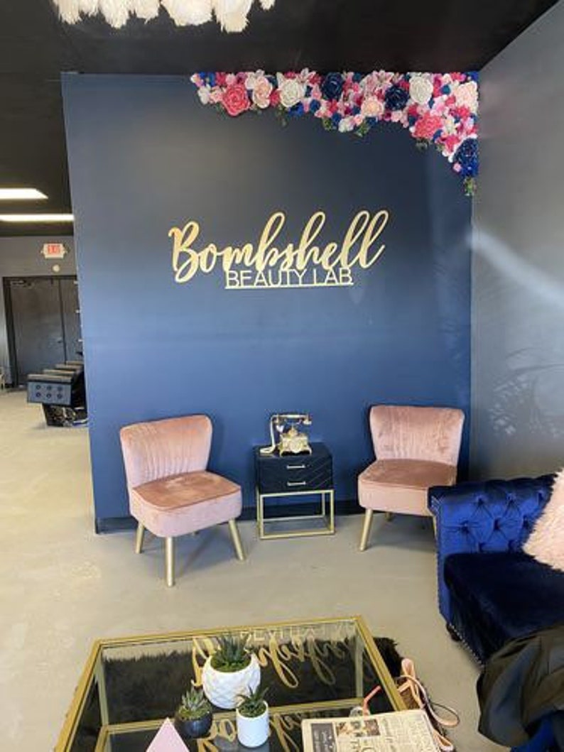 A professional beauty salon showcasing a custom 3D laser-cut logo sign on the wall, crafted in acrylic with raised lettering.
