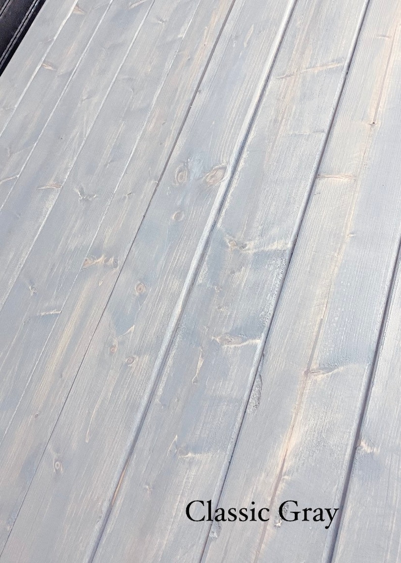 May include: Close-up of a wood surface painted in a light grey colour. The wood grain is visible and the paint has a slightly distressed look. The text "Classic Grey" is printed in black at the bottom of the image.