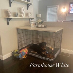 May include: A black metal dog crate with a white top and a black dog inside. The crate is sitting on a wooden floor. The text "Farmhouse White" is written below the crate.
