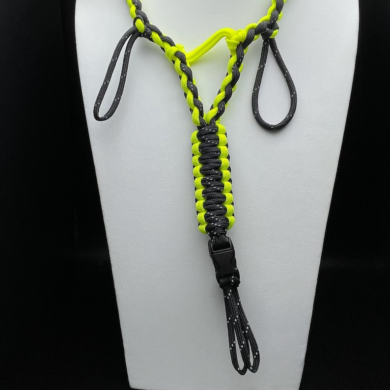 Pu&ograve; includere: Un cordino realizzato in paracord giallo neon e nero con un design intrecciato. Il cordino &egrave; lavorato in una spessa sezione centrale con due anelli superiori e un anello inferiore fissato da una fibbia a sgancio laterale in plastica nera.