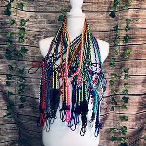Pu&ograve; includere: Una collezione di molteplici cordini in paracord con design intrecciati in vari colori neon e solidi, tra cui arancione, giallo, blu, nero e rosa. Ogni cordino &egrave; dotato di una fibbia in plastica nera e di un occhiello.