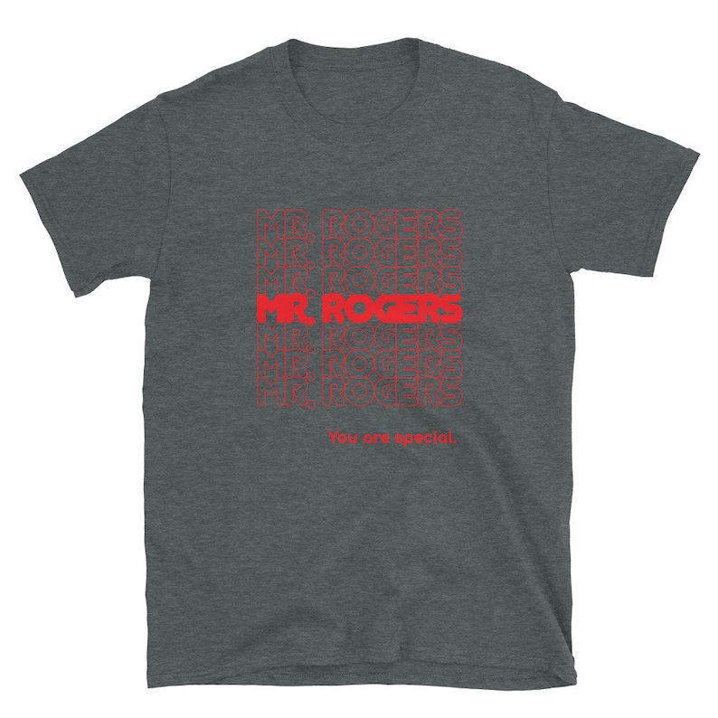 May include: A dark heather grey t-shirt with a red graphic print of the words "Mr. Rogers" repeated multiple times. The text "You are special." is printed below the graphic.